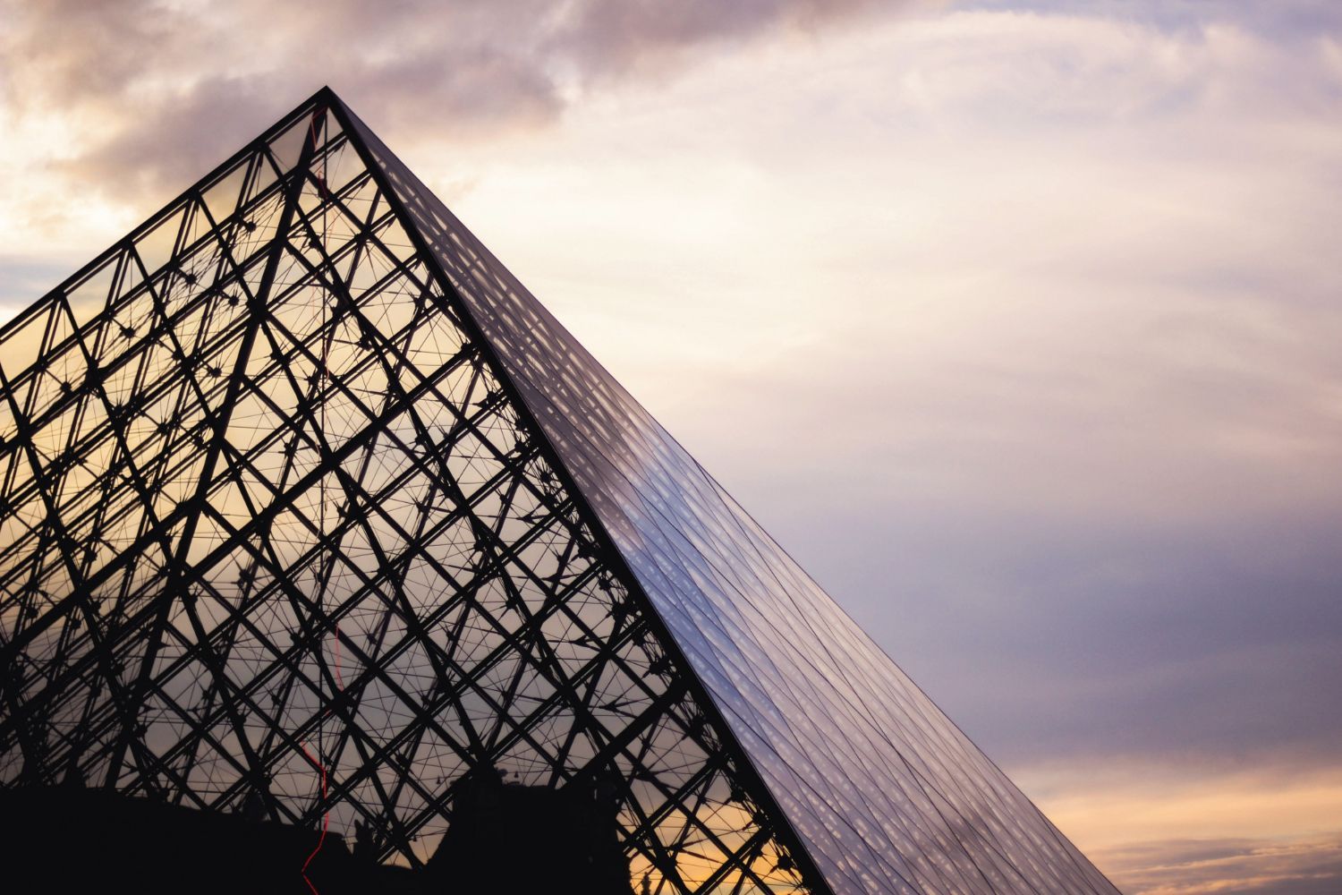 Ein pyramidenförmiges Gebäude mit einem bewölkten Himmel im Hintergrund.