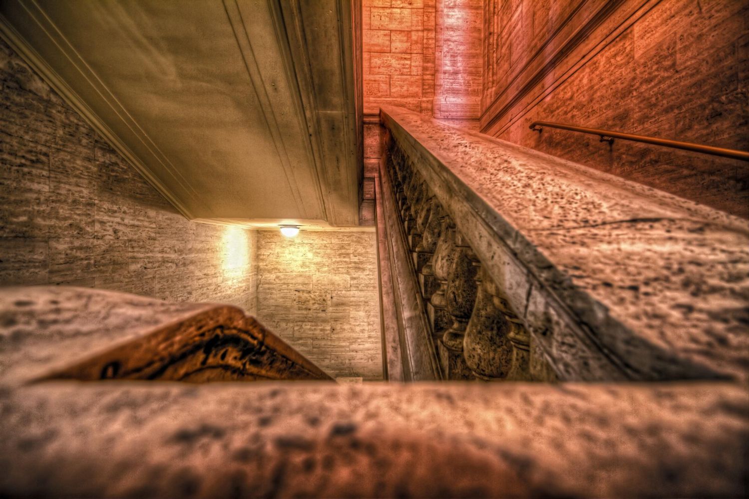 Blick nach oben auf eine Treppe in einem Gebäude mit einer Backsteinmauer.