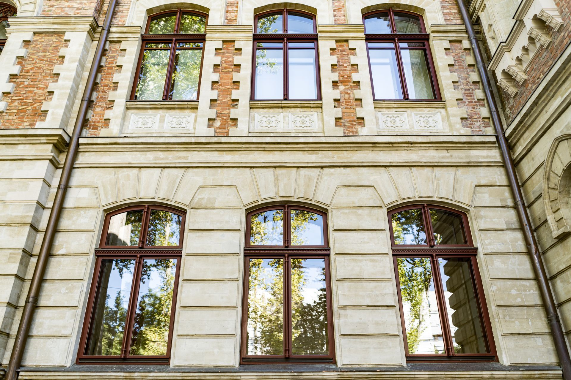 Ein Gebäude mit vielen Fenstern und Bäumen, die sich in den Fenstern spiegeln