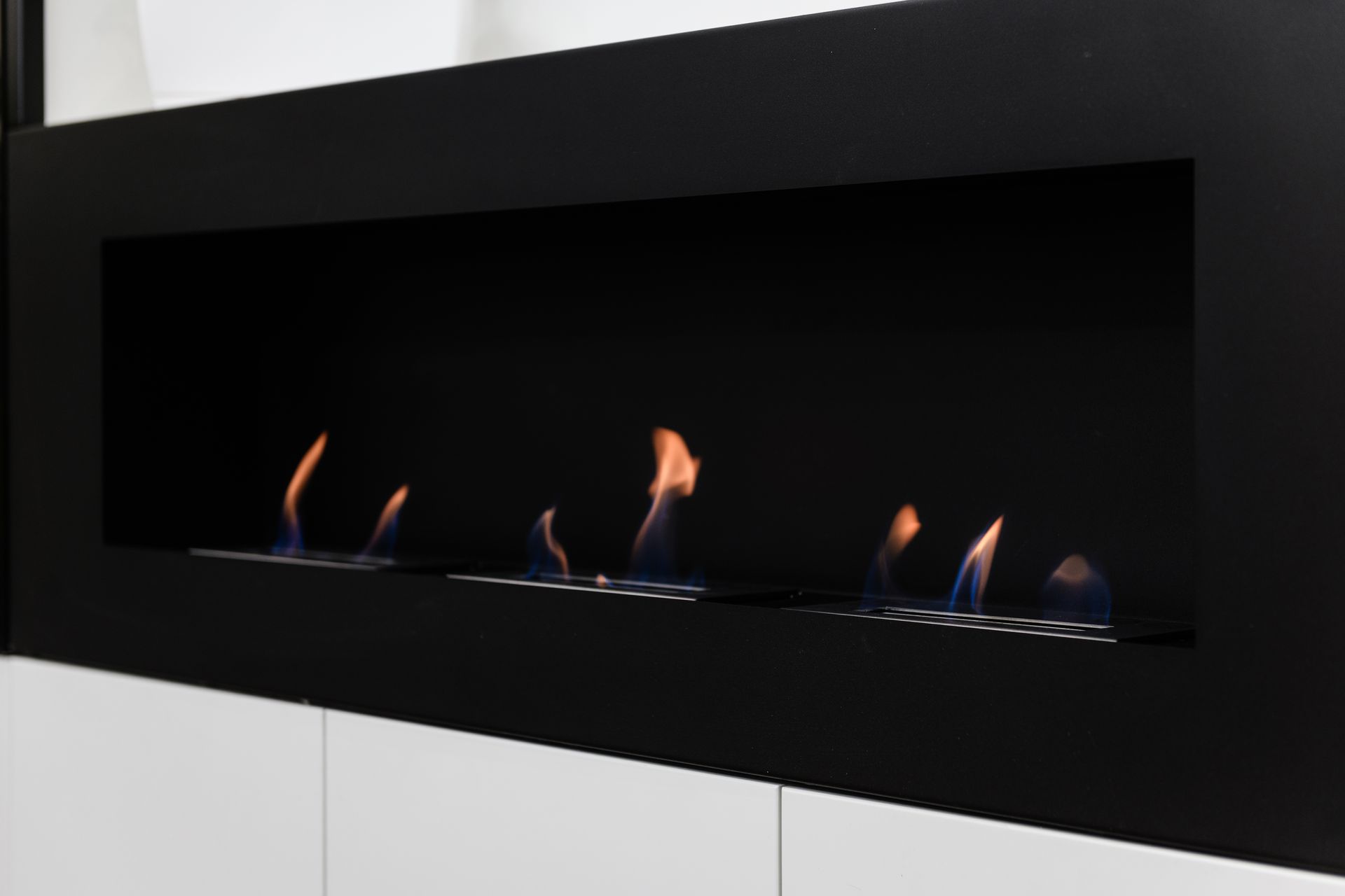 Moderner schwarzer Kamin mit mehreren blauen und orangen Flammen.