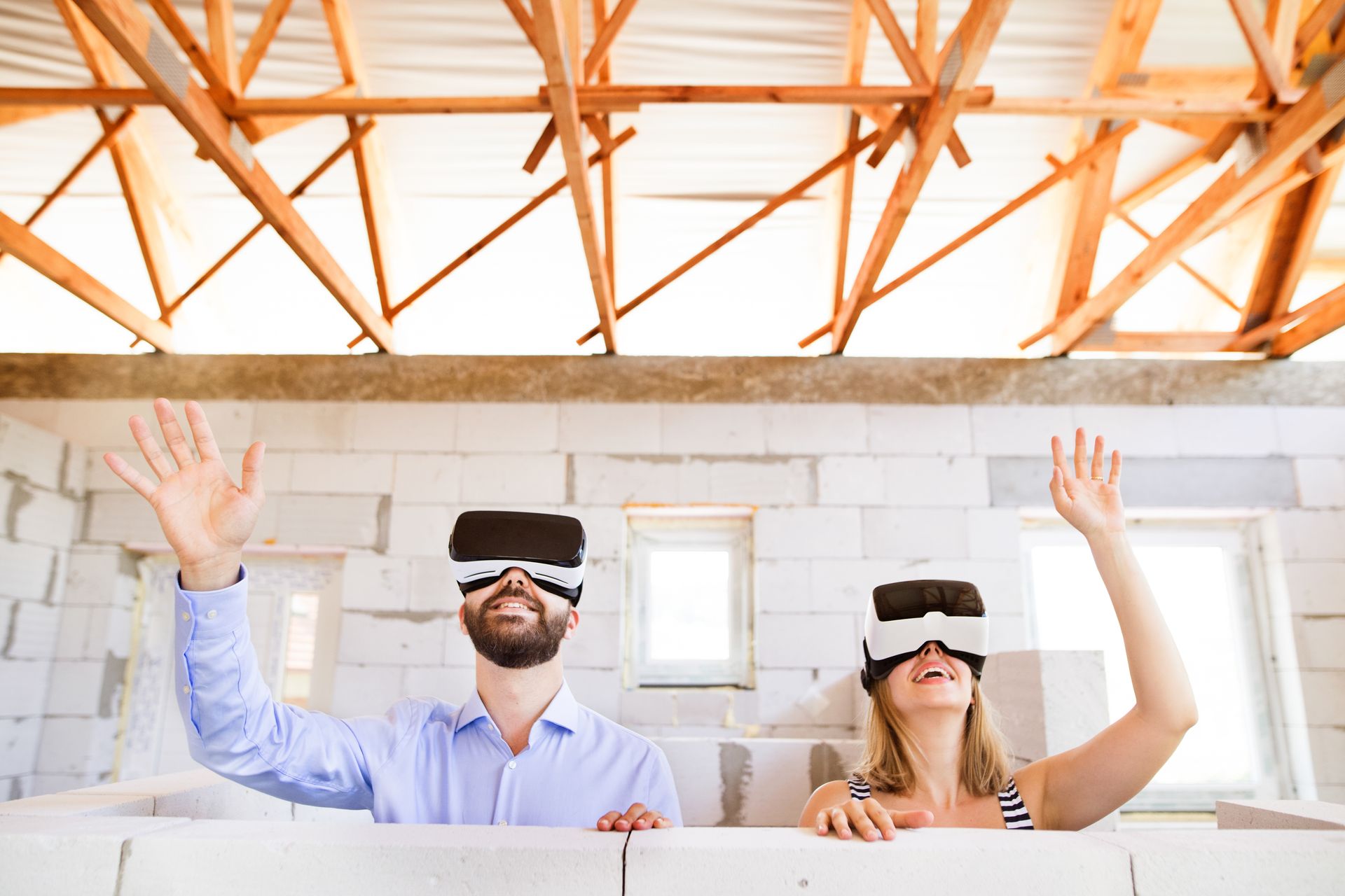Ein Mann und eine Frau tragen Virtual-Reality-Brillen in einem im Bau befindlichen Gebäude.