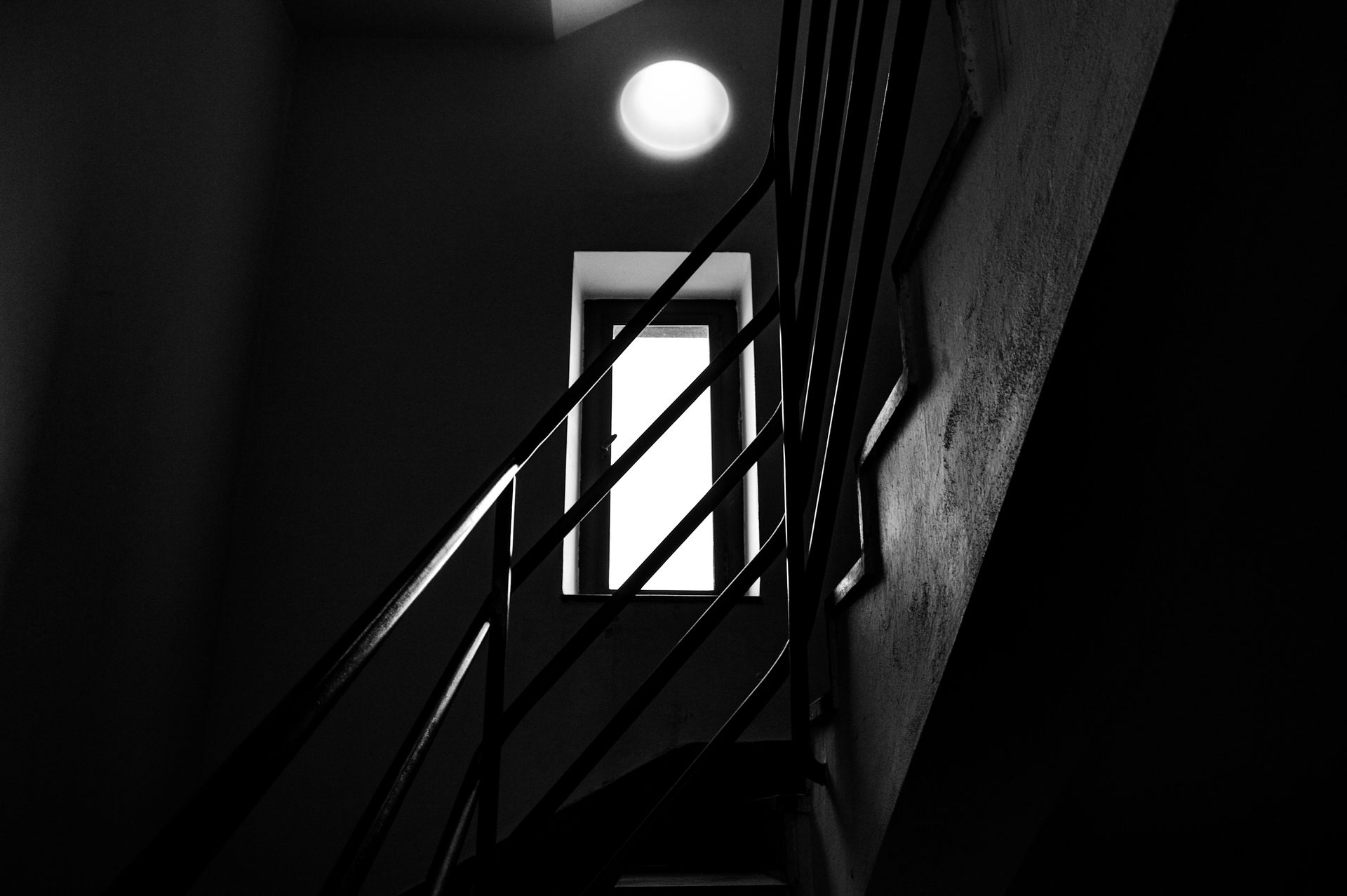 Ein Schwarzweißfoto einer Treppe mit Geländer und Tür.