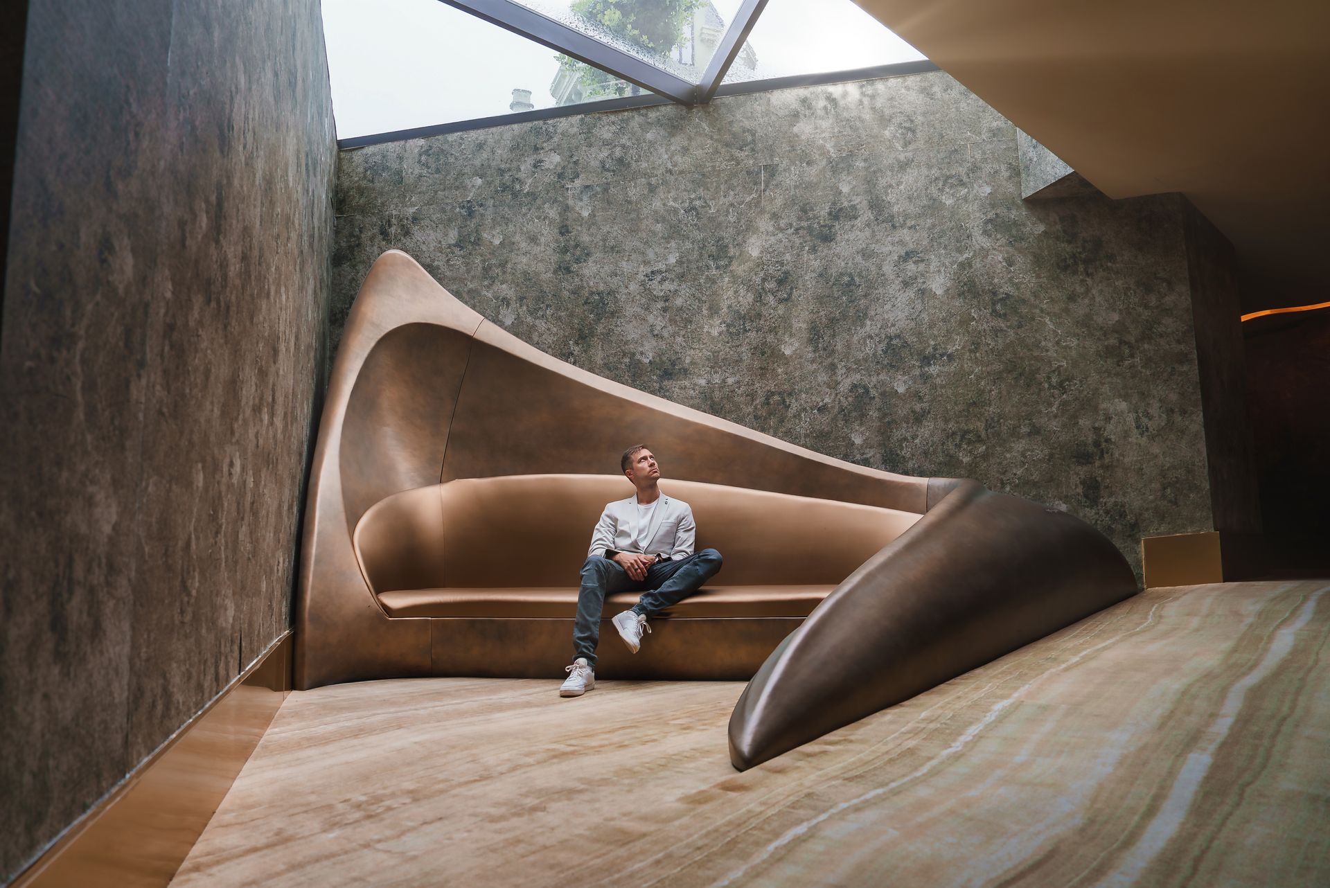 Ein Mann sitzt in einem Zimmer auf einem geschwungenen Sofa.