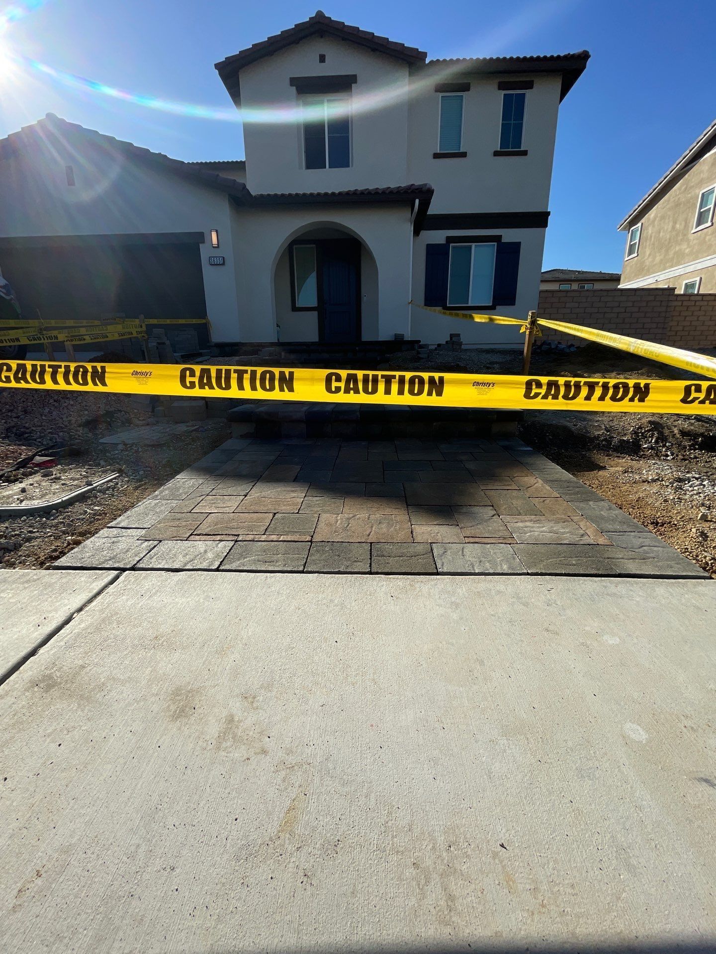 A two-story house with a brick walkway and caution tape in front.