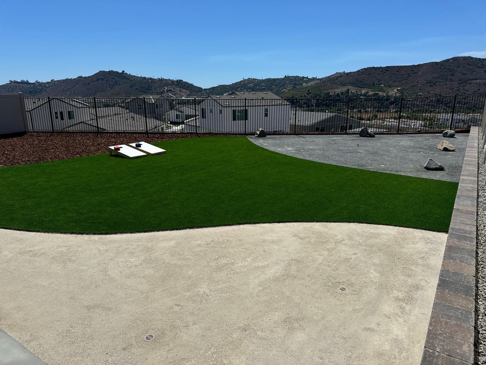 Green lawn and gravel landscaping with a mountain backdrop under a blue sky.