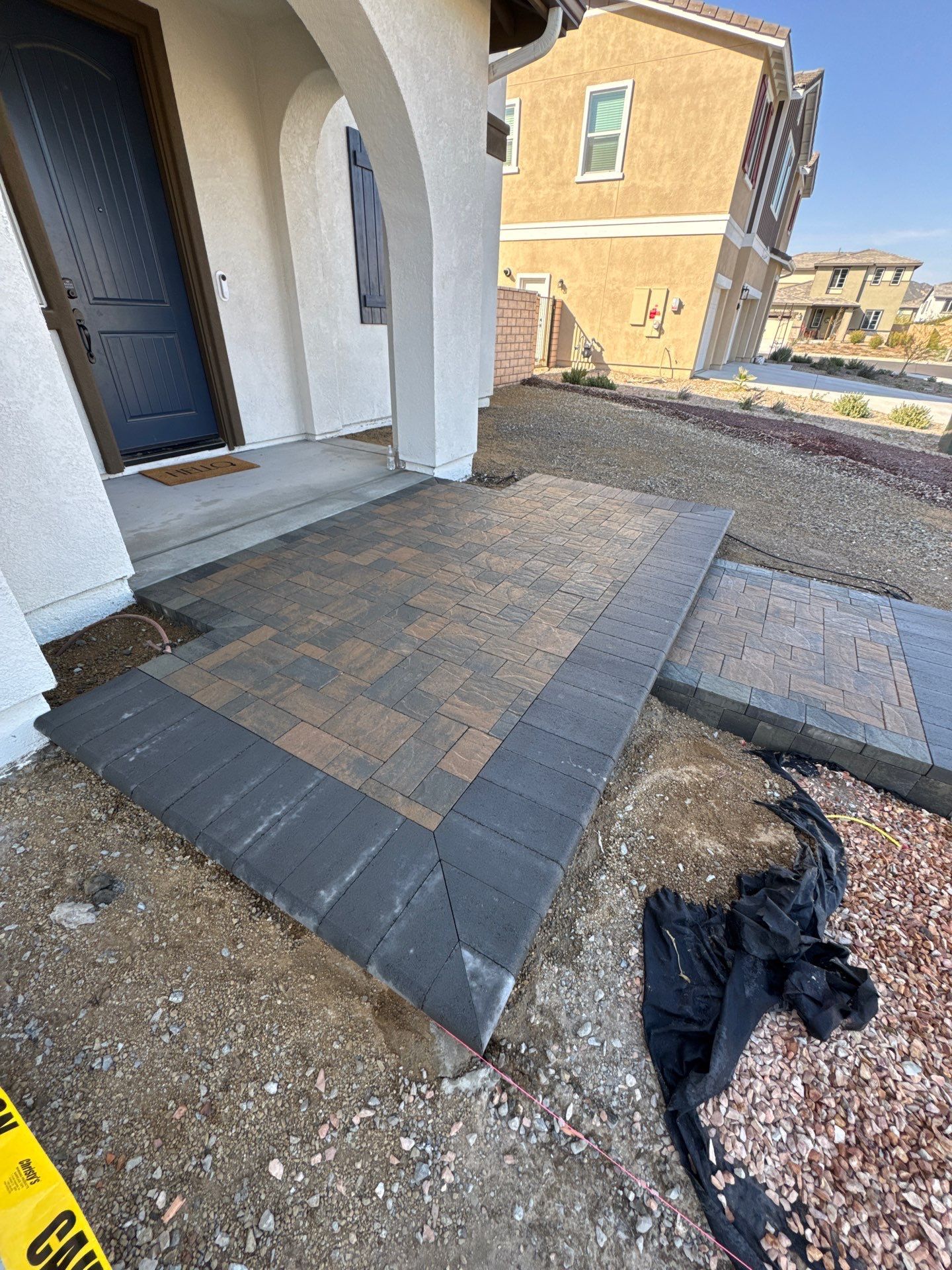 Newly constructed brick front porch with dark border and brown center, near house entrance.