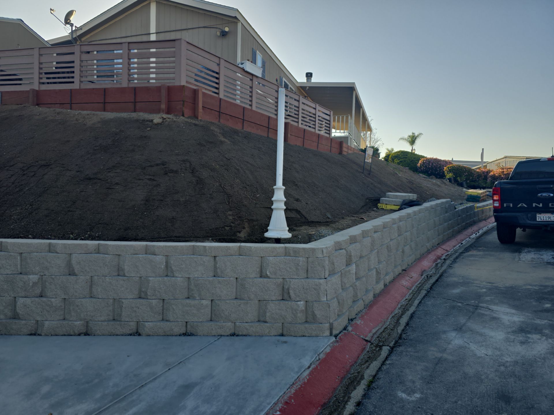 Retaining walls with a building on a hillside; a truck parked on the street.