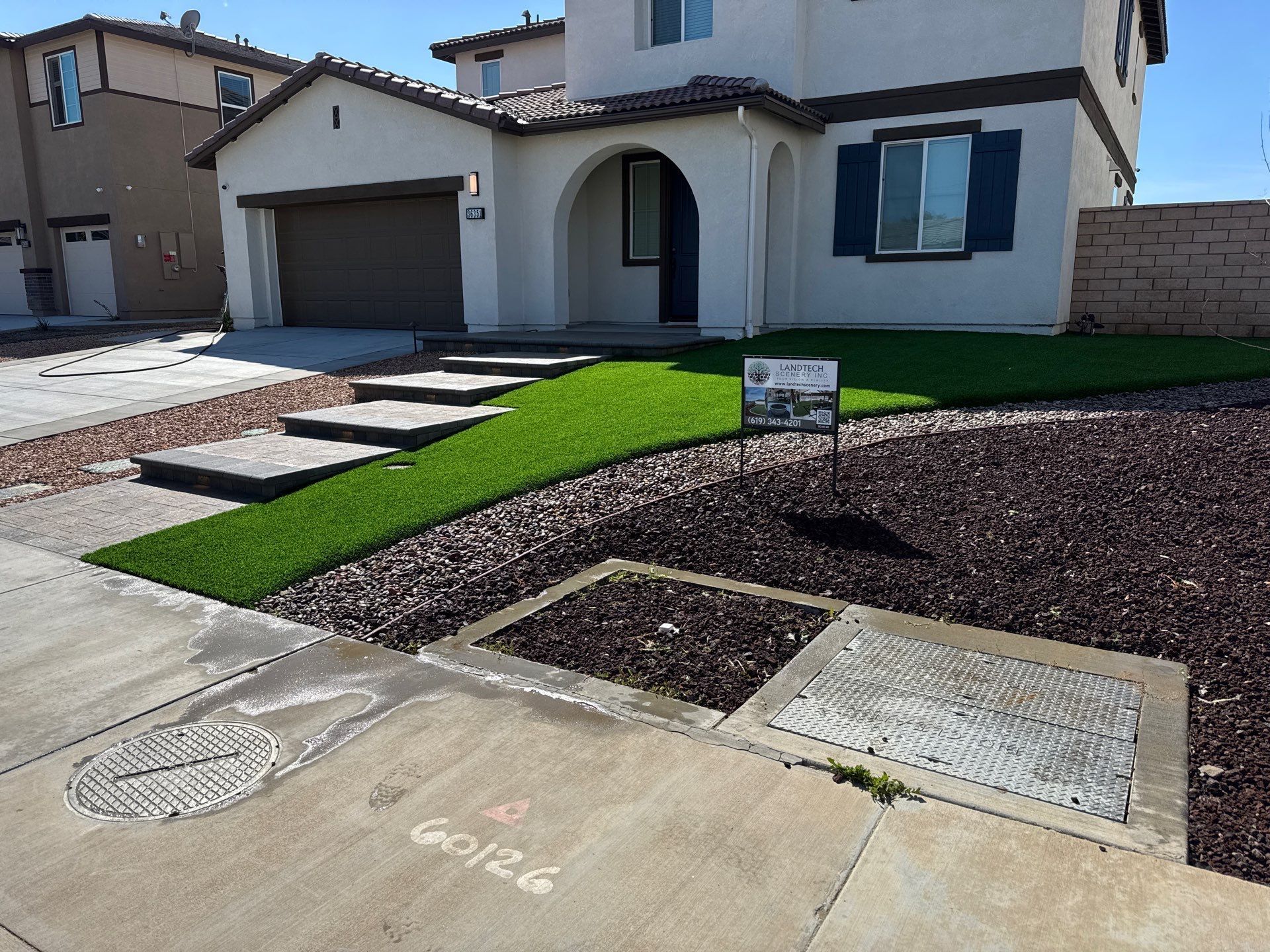 Suburban house with driveway, green lawn, and landscaped front yard under bright sunlight