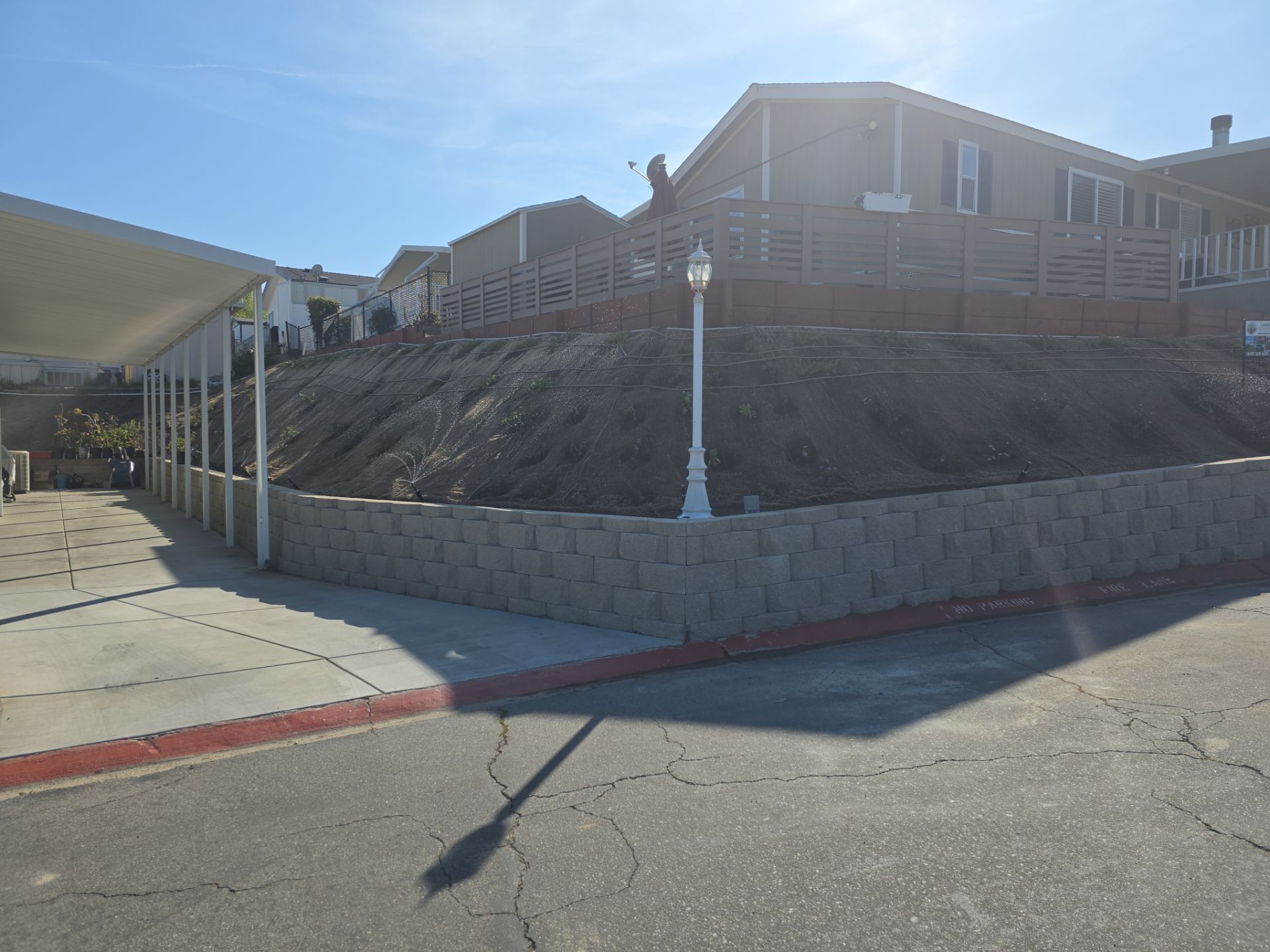 A retaining wall supports a hillside with a building at the top. A person works on top of the hill.