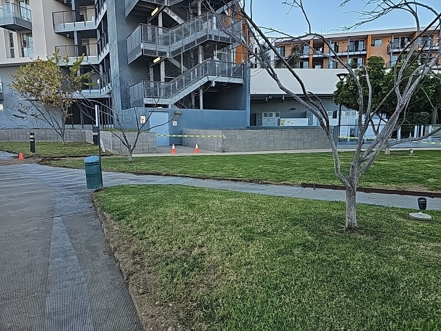 Exterior view of a modern building with a staircase and grassy area with a walking path.