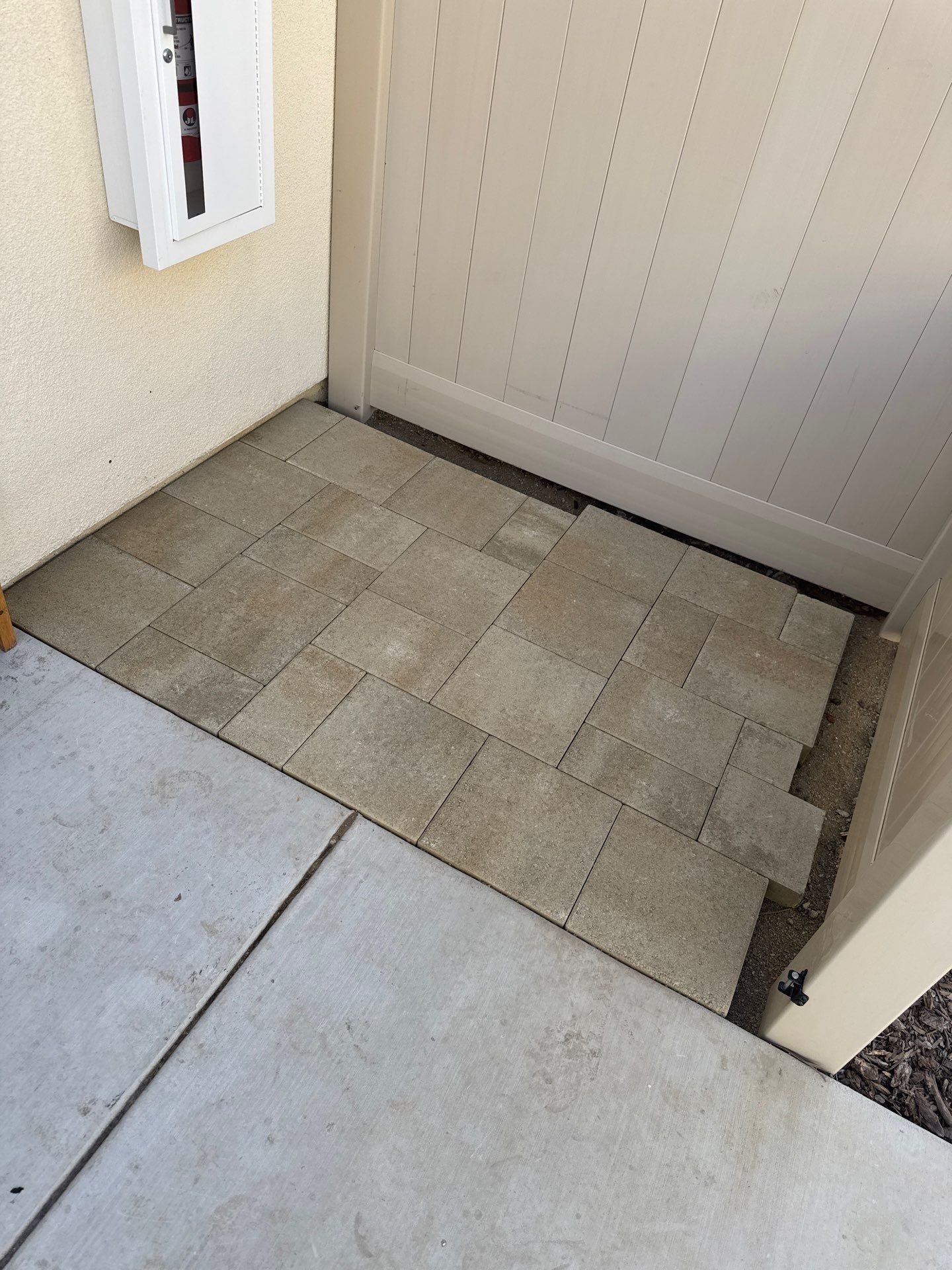 Beige tiled landing area next to a cream-colored fence and concrete sidewalk.