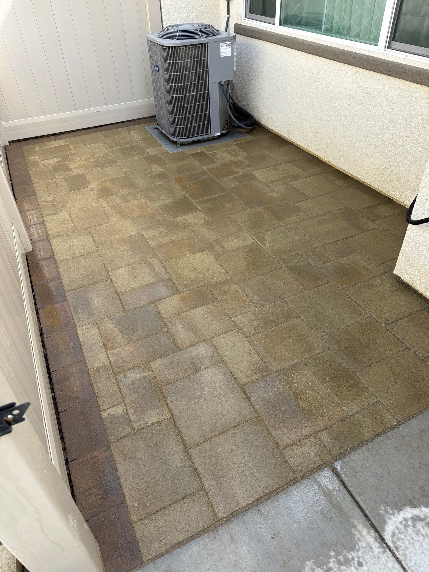 Patio with stone pavers and an air conditioning unit.