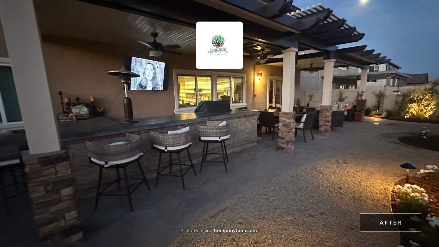 Outdoor bar and patio seating at dusk with a lit screen, stools, and string lights