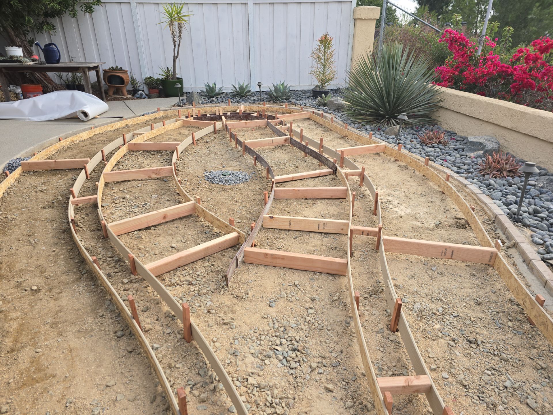 Wooden forms outlining a tiered garden bed in a yard, ready for concrete or planting.