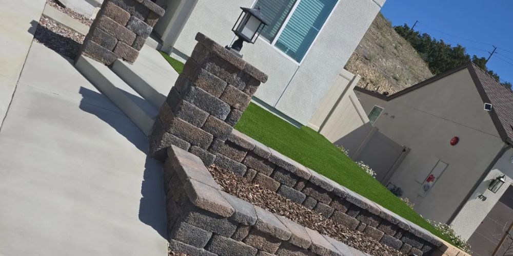 Modern house with stone retaining walls and a sloped lawn under a clear blue sky