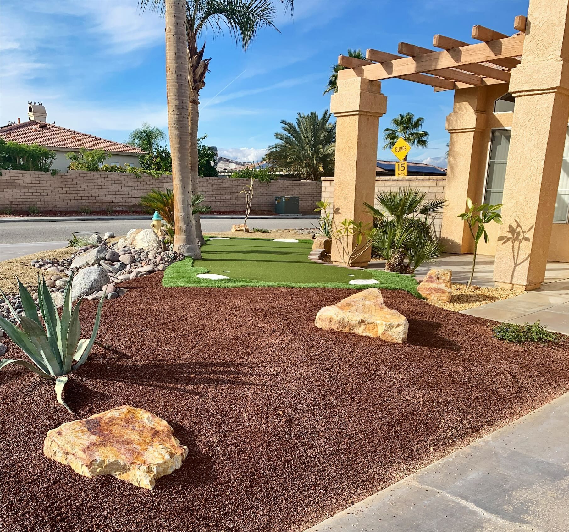 Front yard landscaping with rock, mulch, agave, and a small patch of green turf.