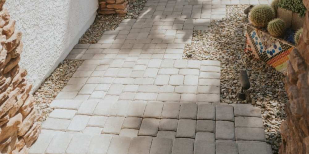 Stone pathway surrounded by walls, gravel, and cacti.