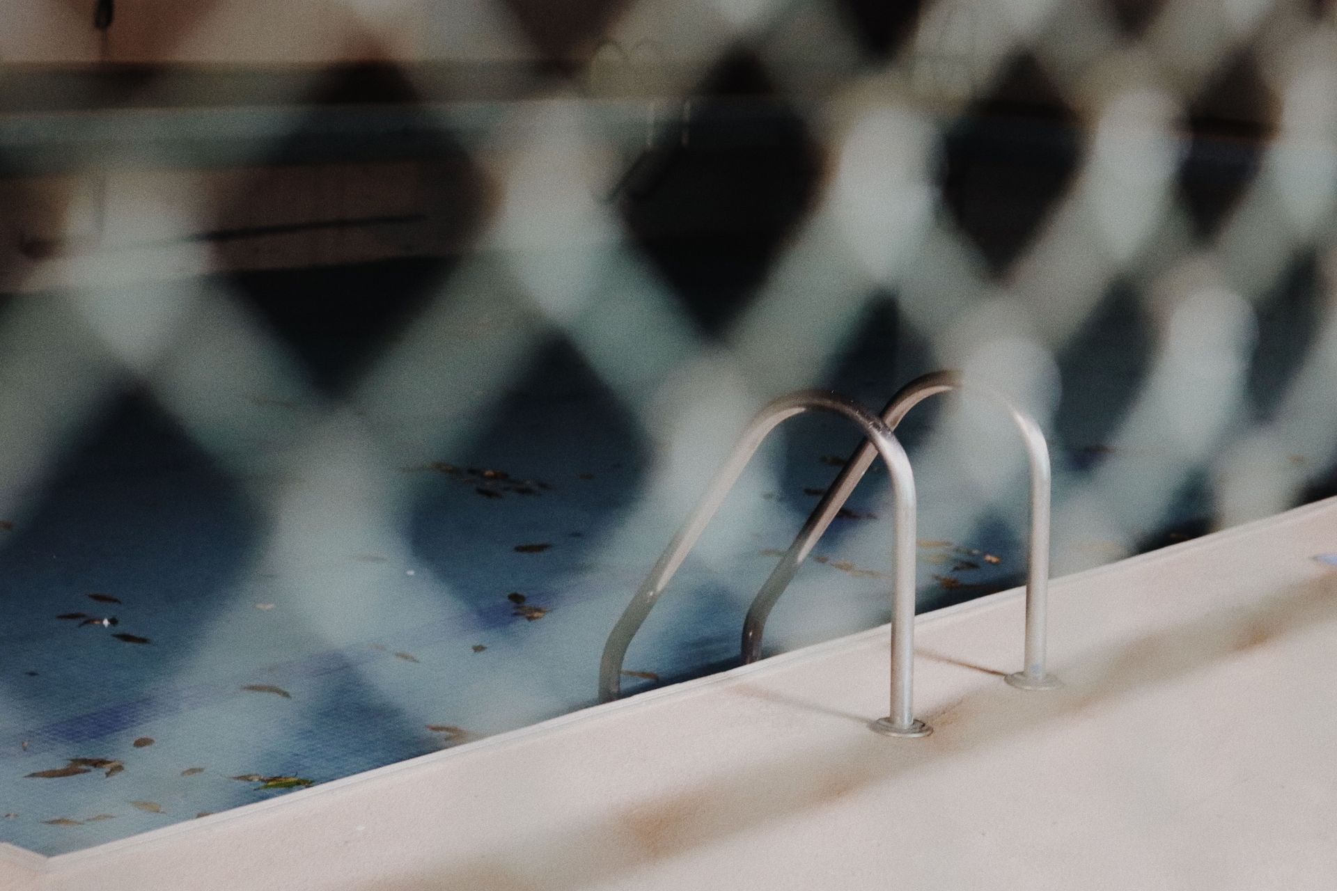 Indoor swimming pool with blue water and a metal ladder beside the deck