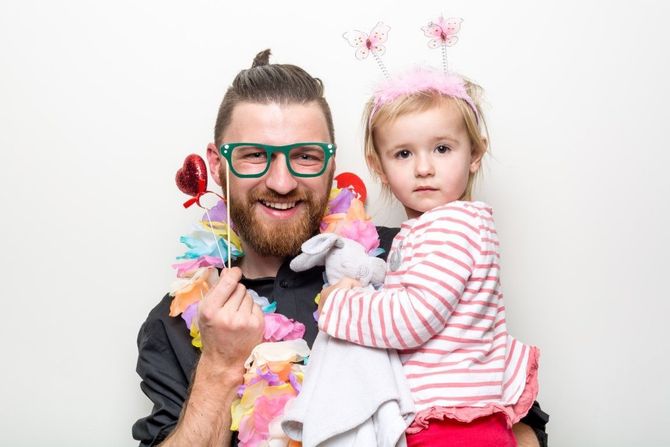 Smiling adult and young child in colorful costumes, posing against a white background