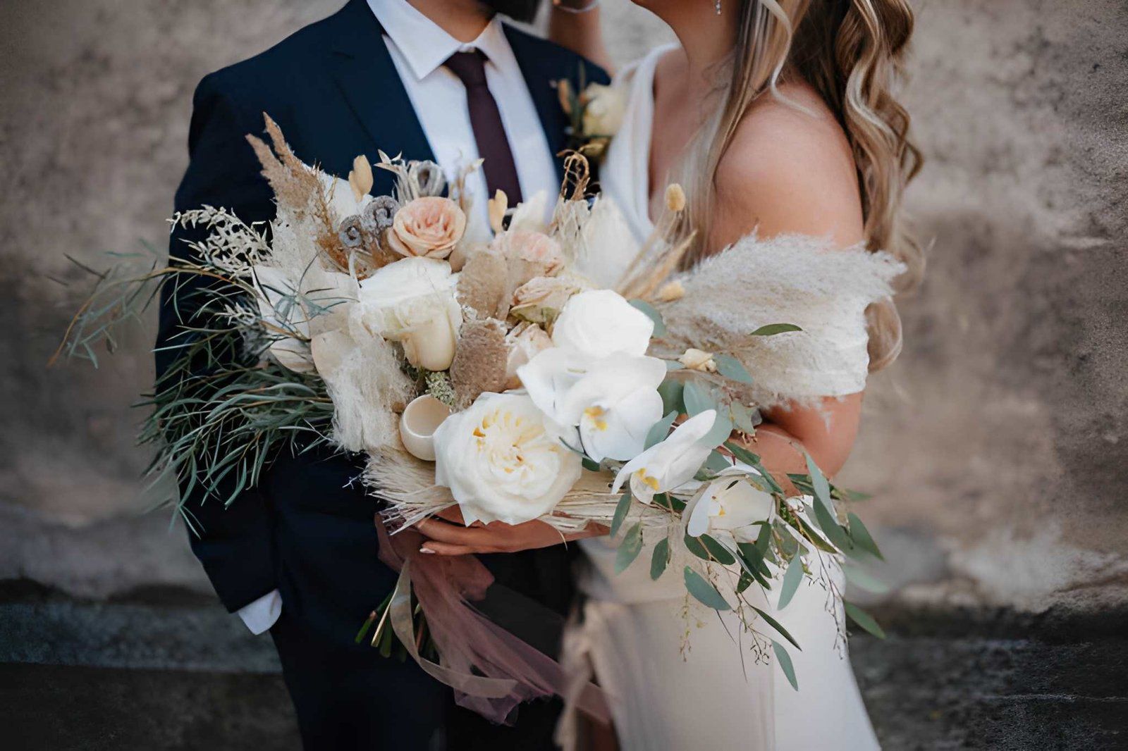 Couple in formal attire holding a cream-and-white floral bouquet