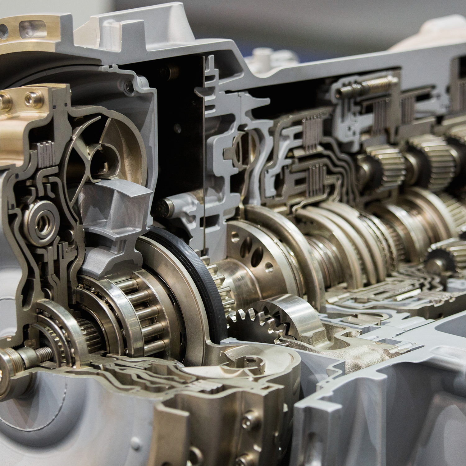 Cutaway view of a metallic engine gearbox, showing internal gears, shafts, and bearings in silver tones