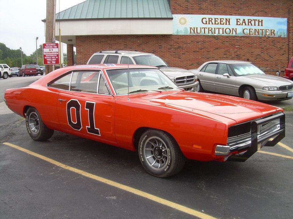 Orange classic car with the number 01 parked outside a nutrition center.