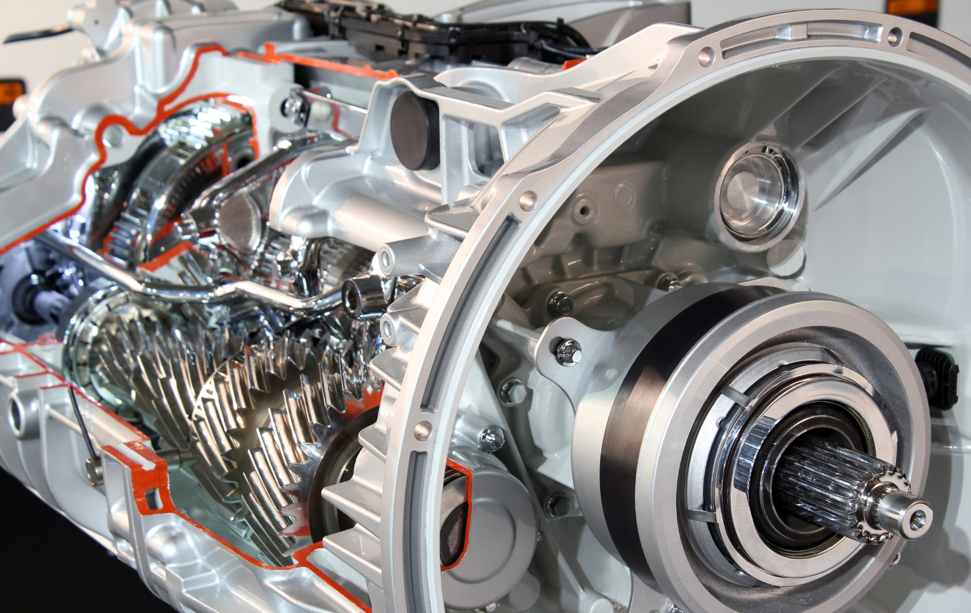 Cutaway view of a car transmission showing gears, shafts, and metal housing with orange wiring