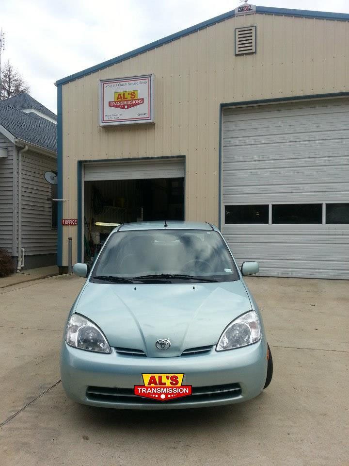 Light blue compact car parked outside an auto repair shop garage