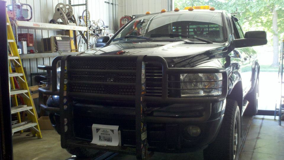 Black pickup truck in a garage, facing forward with a heavy grille guard.