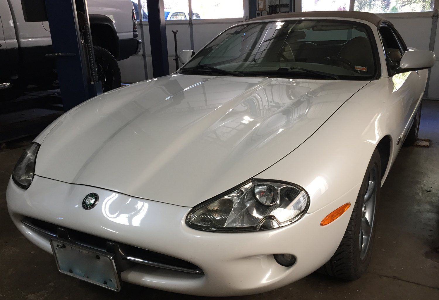 White sports car parked indoors in a garage, front view