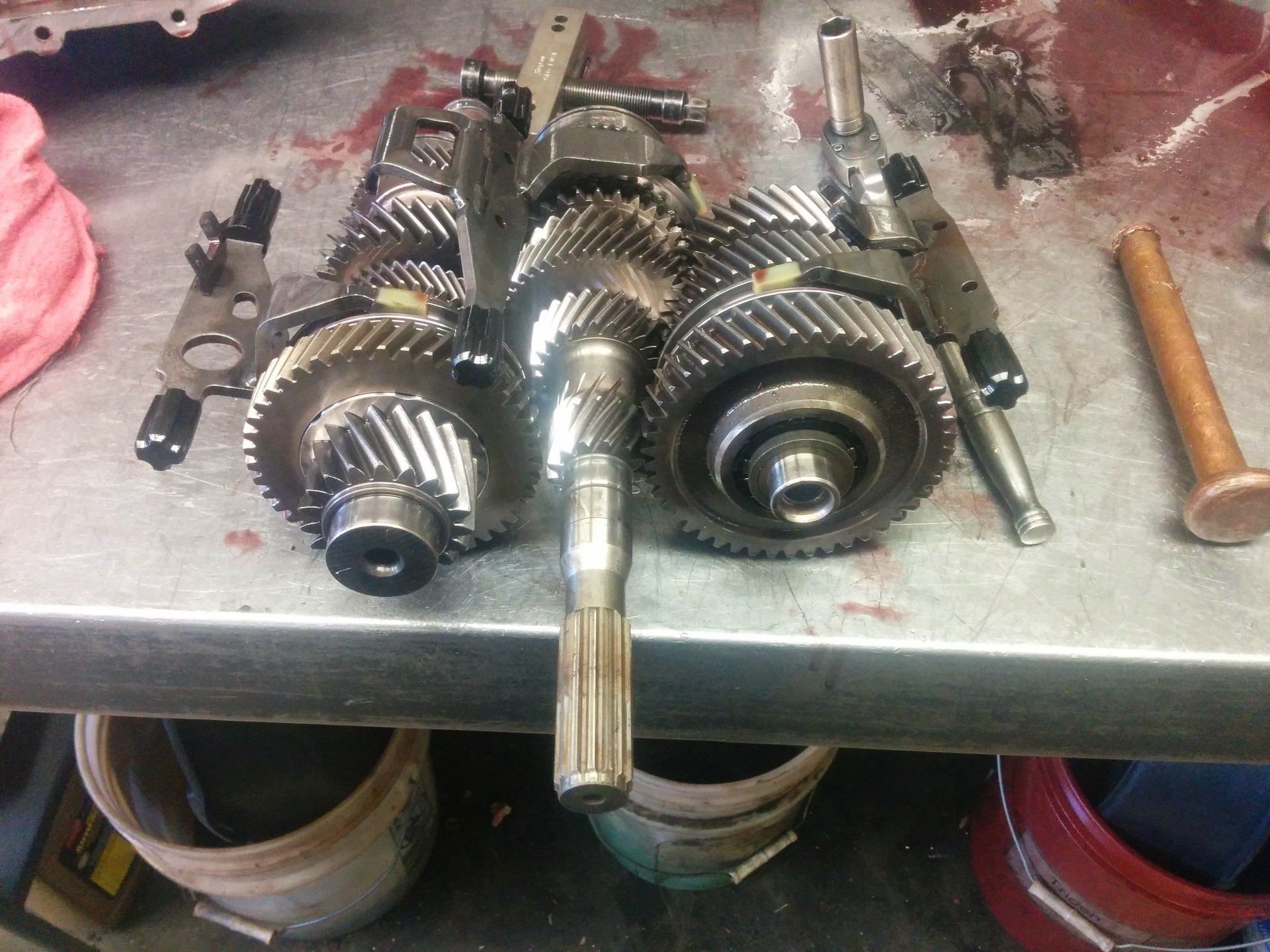 Disassembled metal gears and shafts laid out on a workbench in a workshop