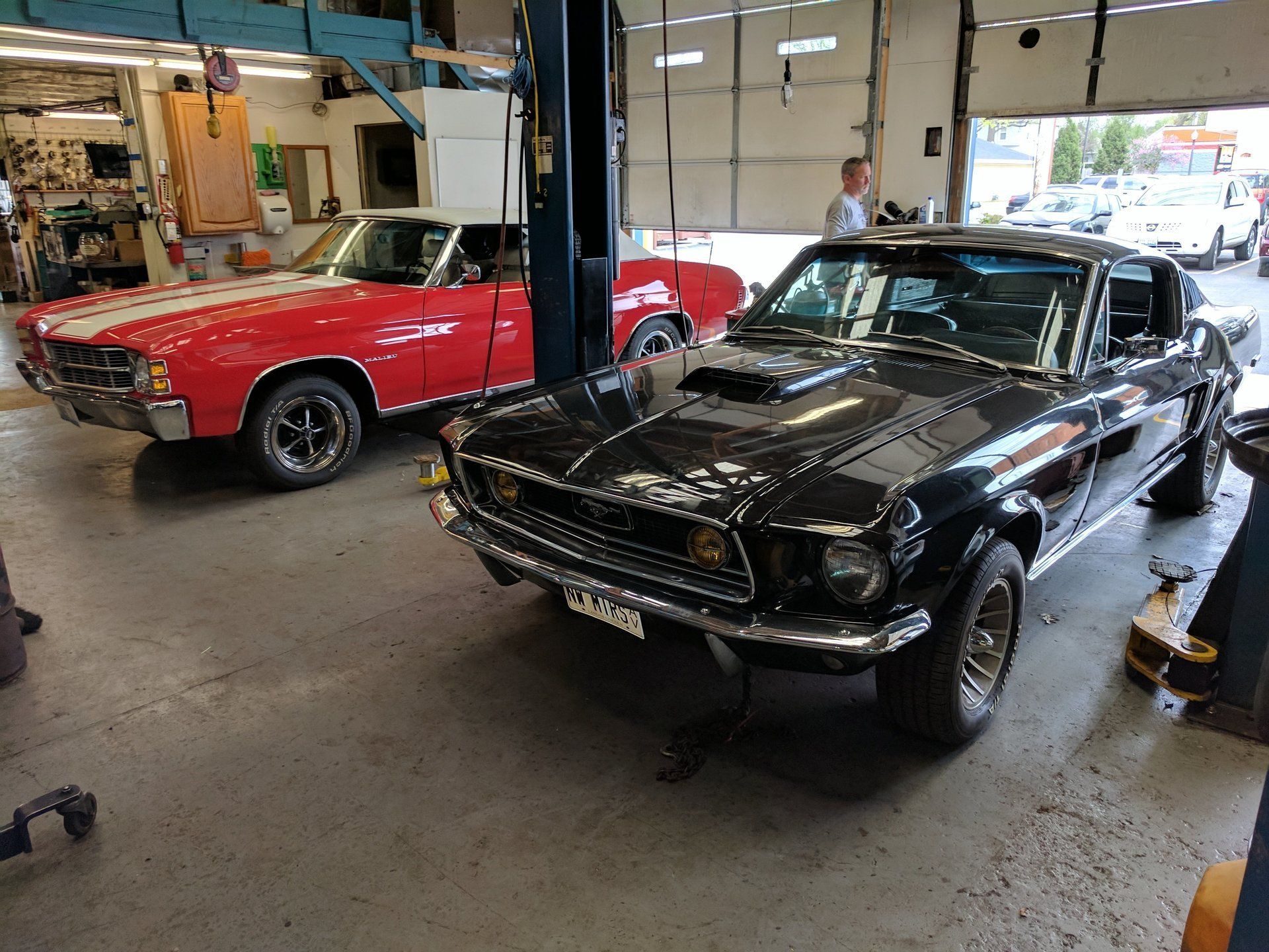 Black classic car and red convertible in a garage workshop