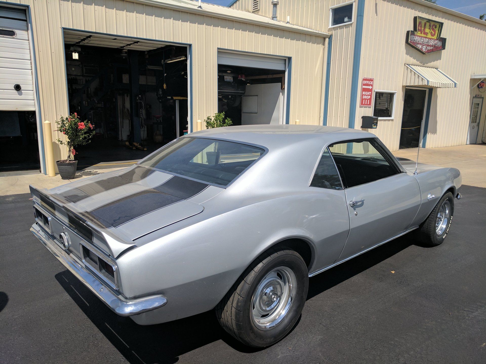 Silver classic muscle car parked outside a garage building