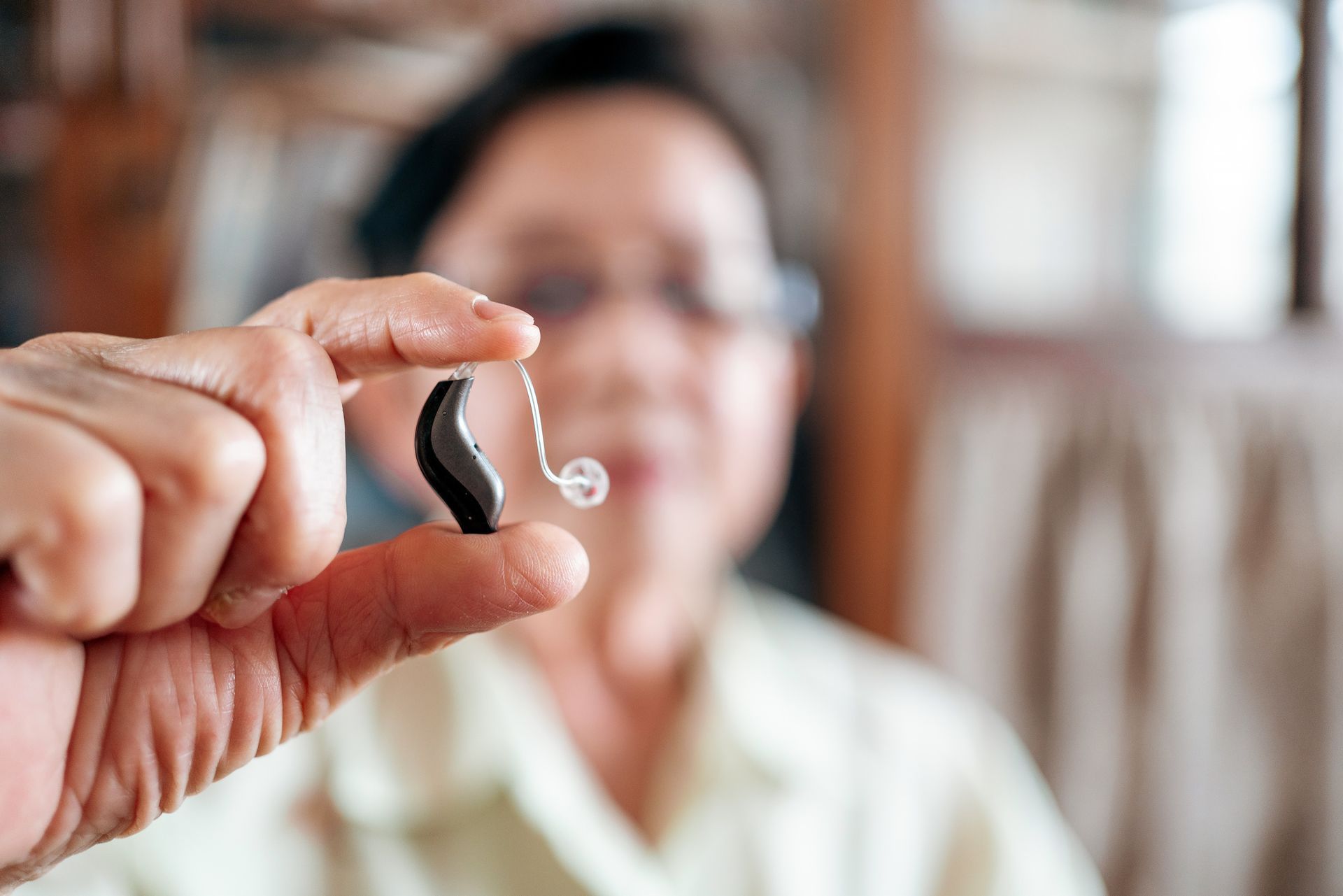 Person holding a hearing aid up to the camera.