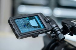 Close-up of a camera monitor displaying a blue circuit board on a tripod mount