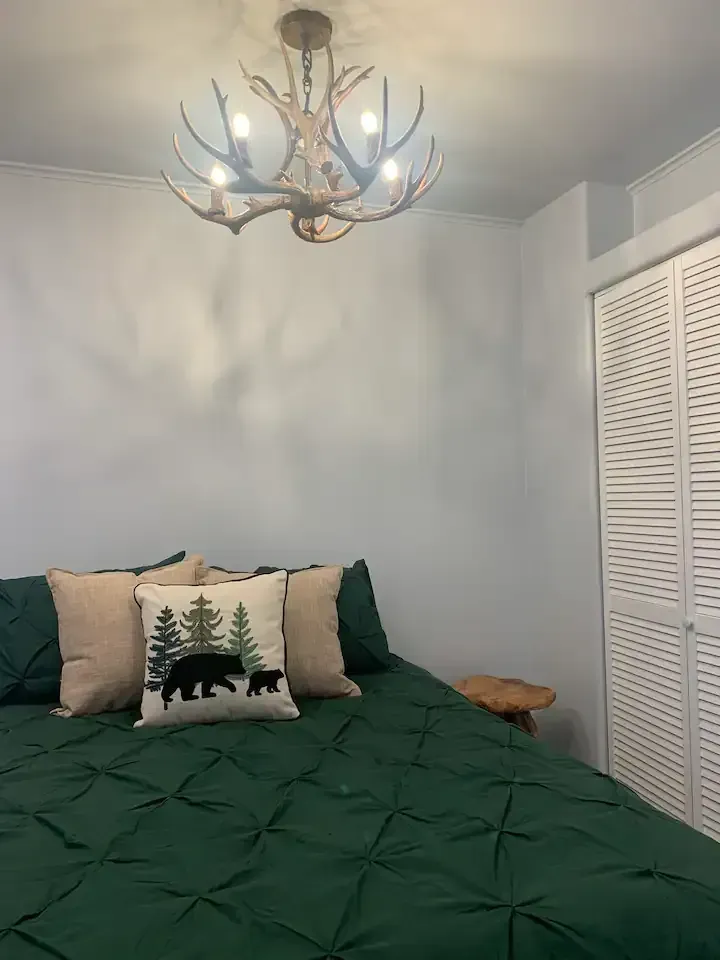 A bedroom with a bed and a chandelier hanging from the ceiling.