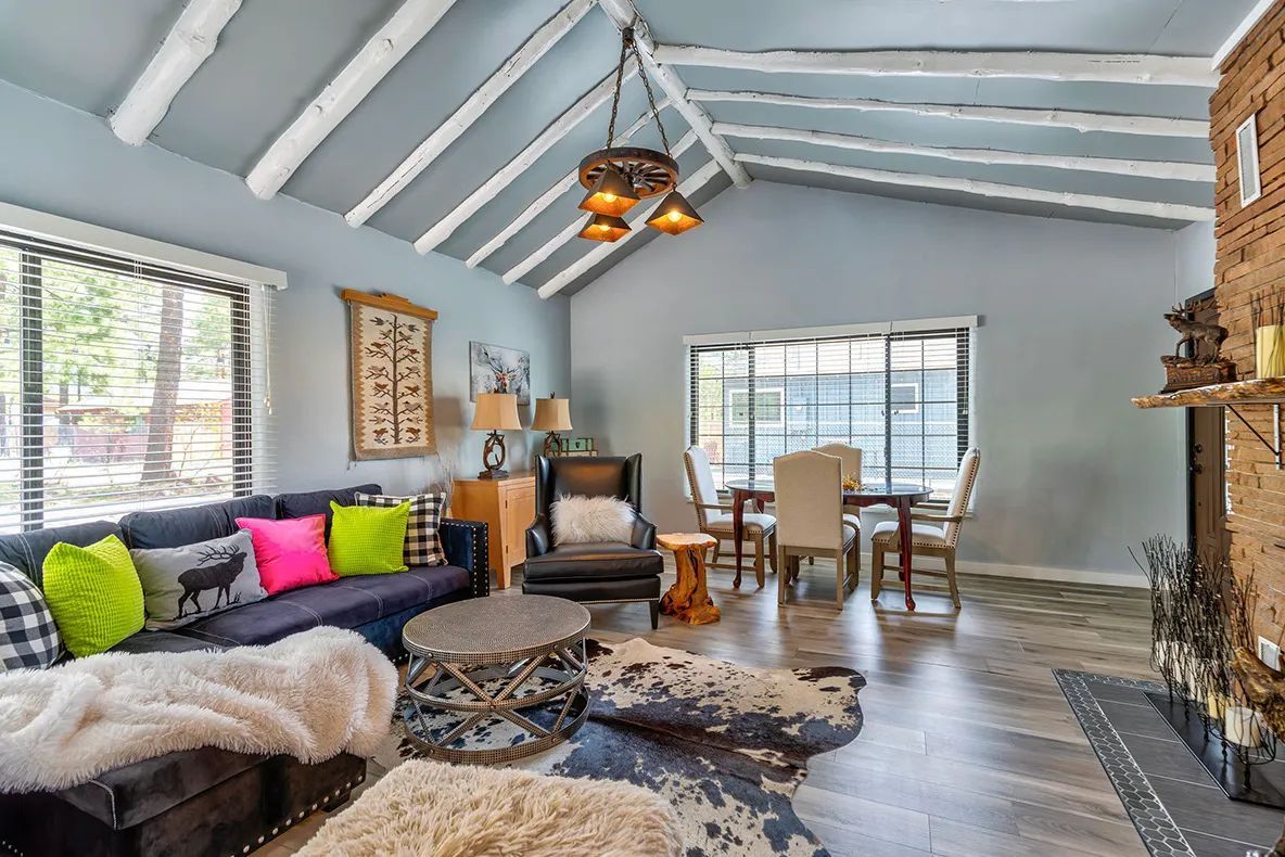 Cozy living room with gray walls, fireplace, sofa, patterned rug, and dining table by the window.