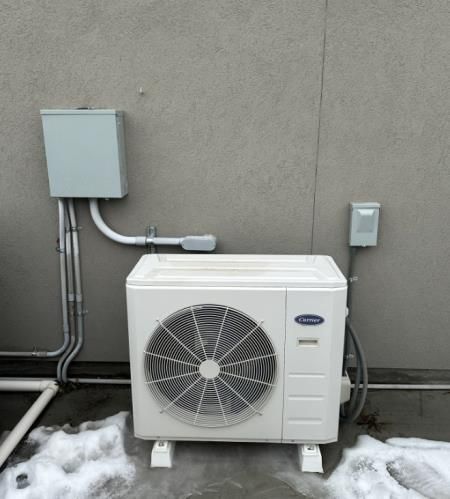 Three men are working on an air conditioner outside of a building.