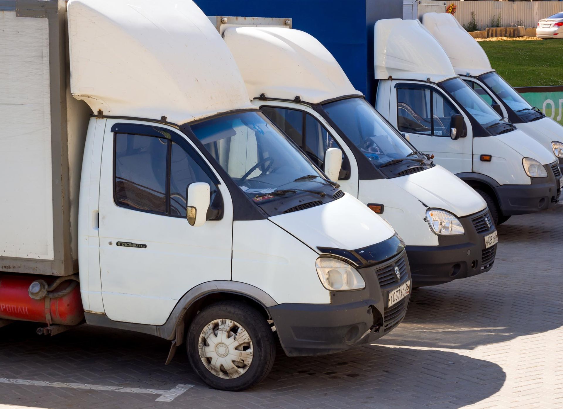 Three white delivery trucks parked in a row outdoors
