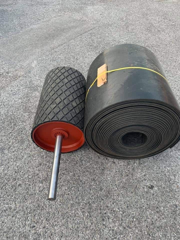 A Roll of Rubber Belt Next to A Roller on The Ground — Conveyor Maintenance Services In Innisfail, QLD