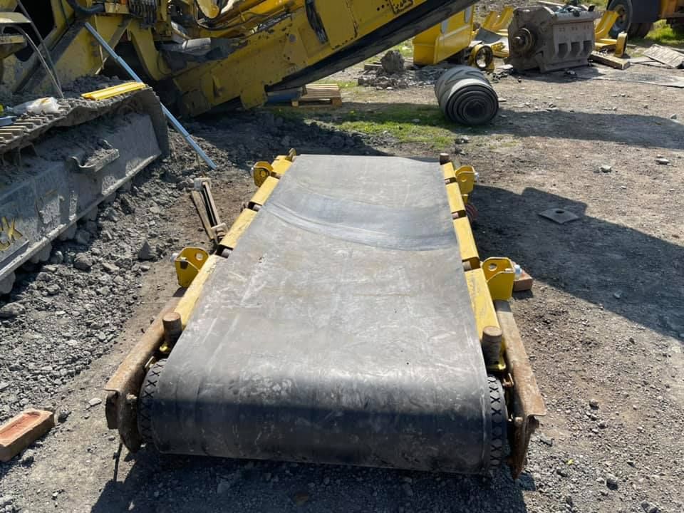 A Conveyor Belt Is Sitting in The Dirt Next to A Machine — Conveyor Maintenance Services In Ayr, QLD