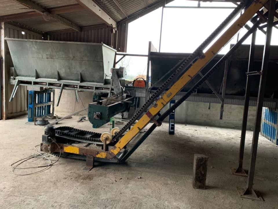 A Conveyor Belt Is Sitting in A Warehouse Next to A Machine — Conveyor Maintenance Services In Charters Towers, QLD