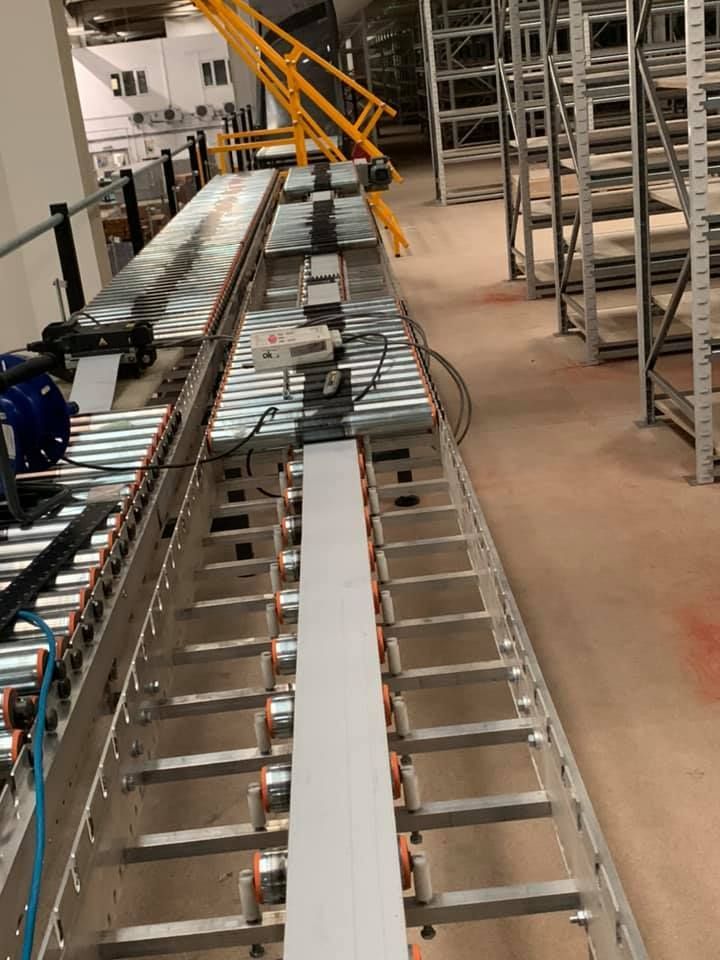 A Conveyor Belt Is Going Down a Warehouse Floor — Conveyor Maintenance Services In Ingham, QLD