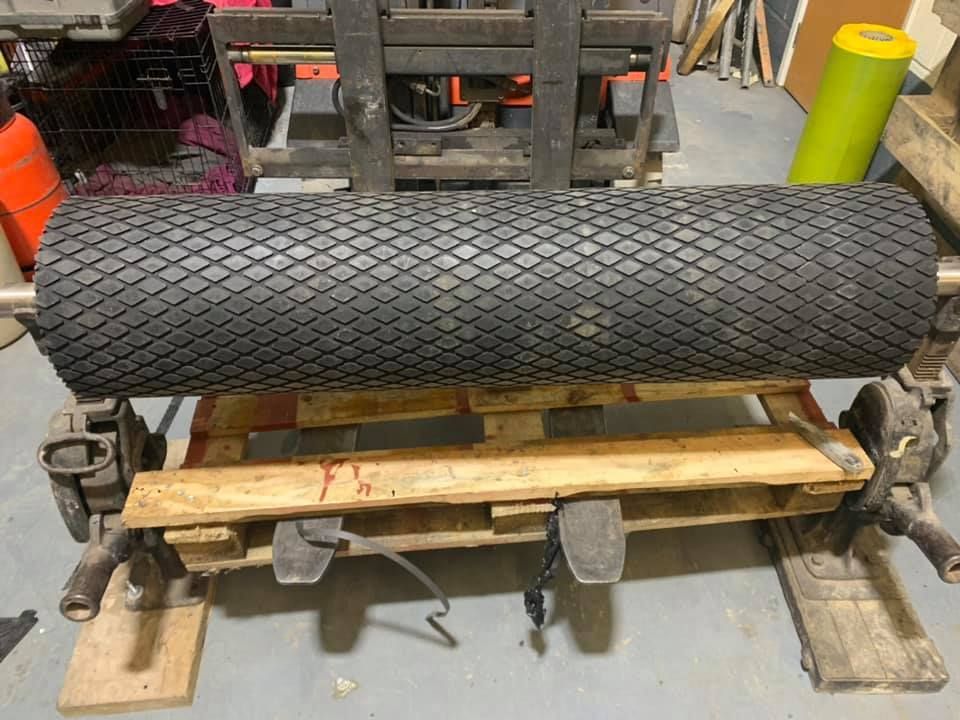 A Large Tire Is Sitting on A Wooden Pallet Next to A Forklift — Conveyor Maintenance Services In Ingham, QLD