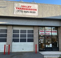 Valley Transmission auto shop storefront with garage door, glass entrance, and sign above the building.