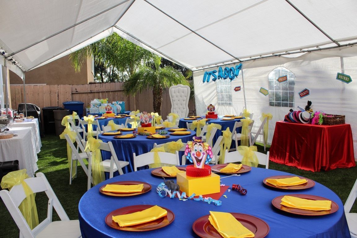 Decorated outdoor party tent with round tables, blue and red tablecloths, and colorful place settings