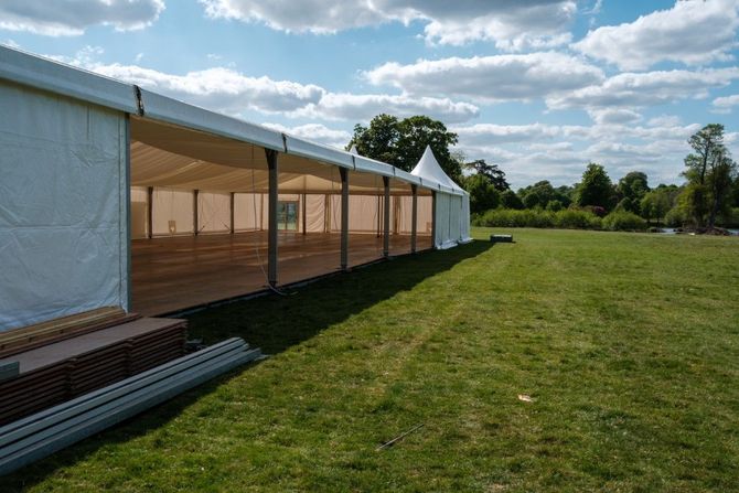 White event tent beside a grassy field under a blue sky