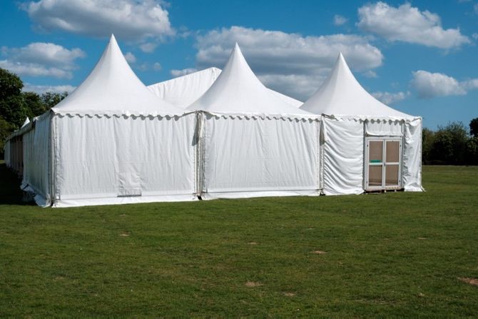 White event tents on a grassy field under a blue sky