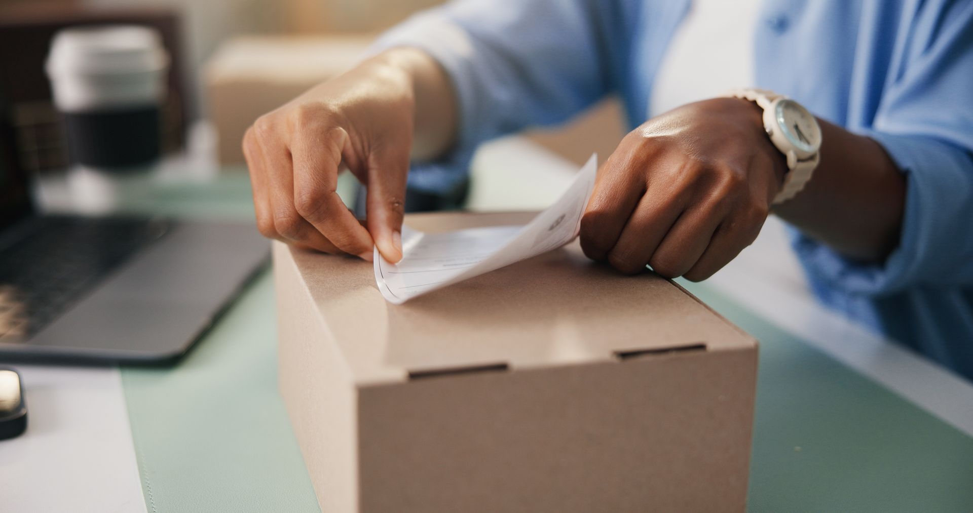 Hands placing a shipping label on a package box for delivery and logistics.