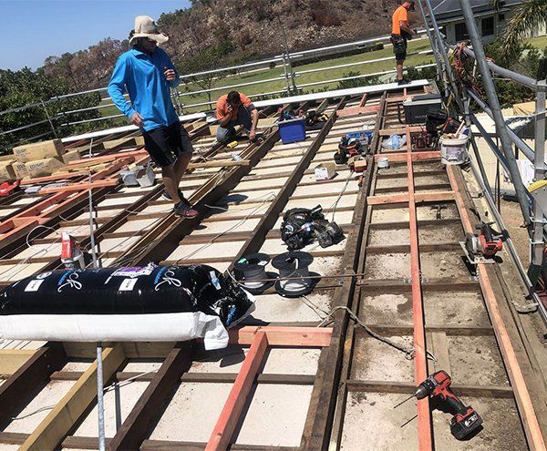 A Group Of Construction Workers Are Working On A Roof — Posty’s Roofing In Airlie Beach, QLD